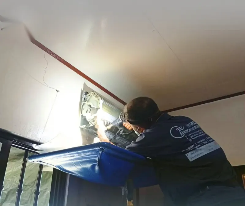 A technician washing the coils and blower of a split-type indoor unit